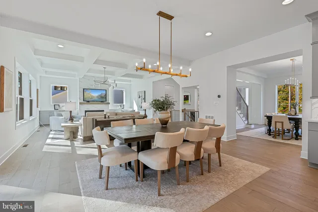 a view of a dining room and livingroom with furniture wooden floor a rug a flat screen tv a painting and a chandelier