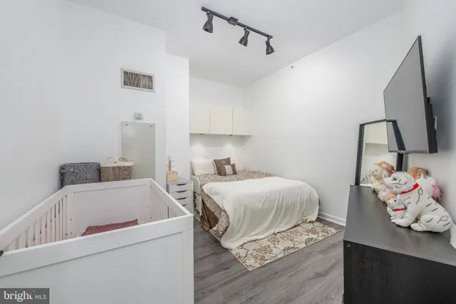 a bedroom with a bed and a flat tv screen on the dresser