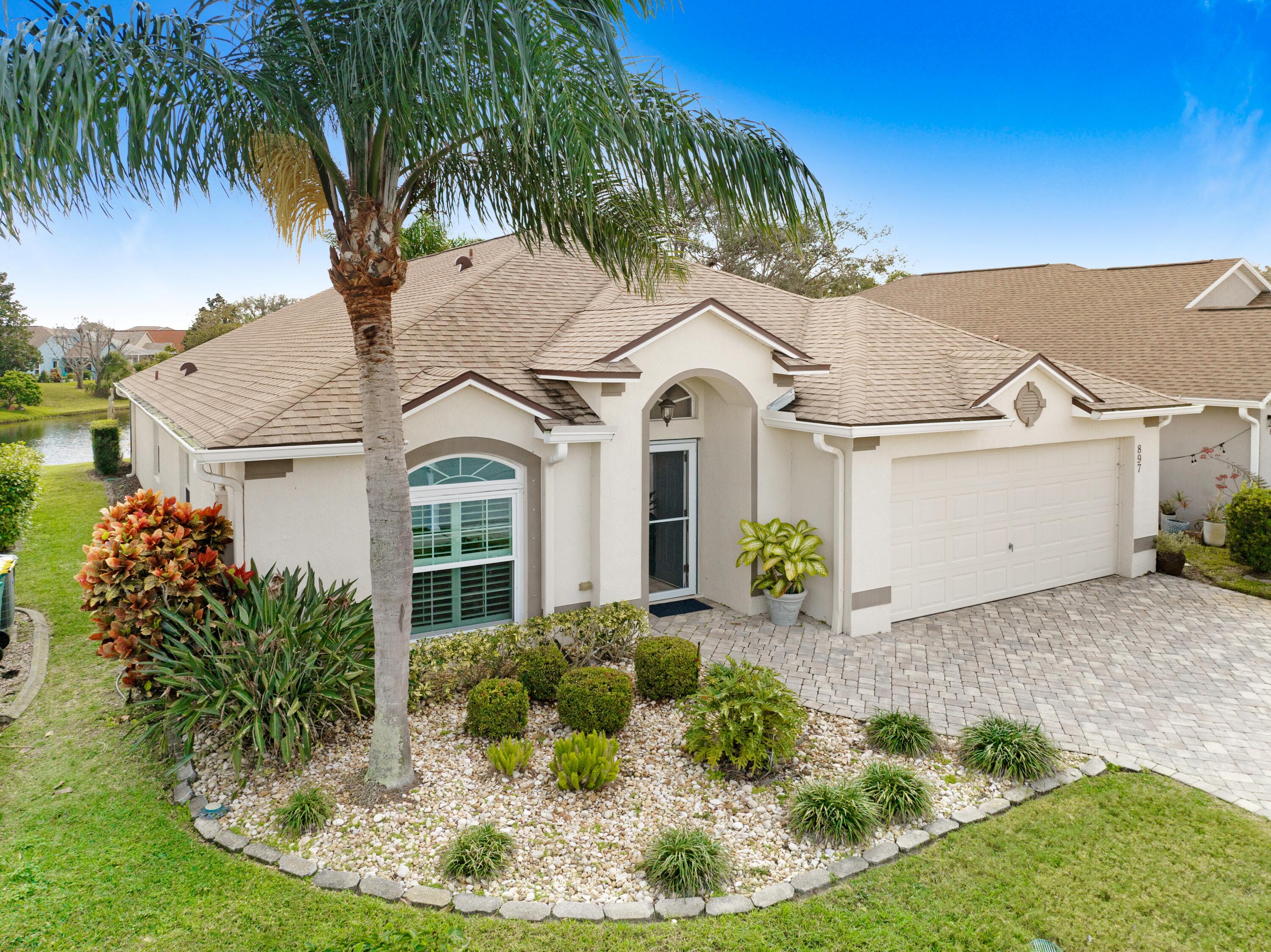 897 Shaw Circle Melbourne, FL 32940 - Photo 4 of 57 a view of a white house with a swimming pool and lawn chairs under palm trees