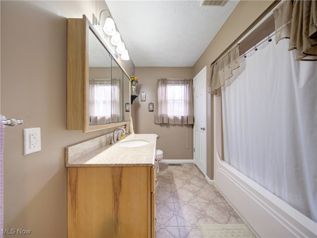 17161 Burrows Road Thompson, OH 44086 - Photo 17 of 48 Full bathroom with shower / bathtub combination with curtain, vanity, toilet, and a textured ceiling