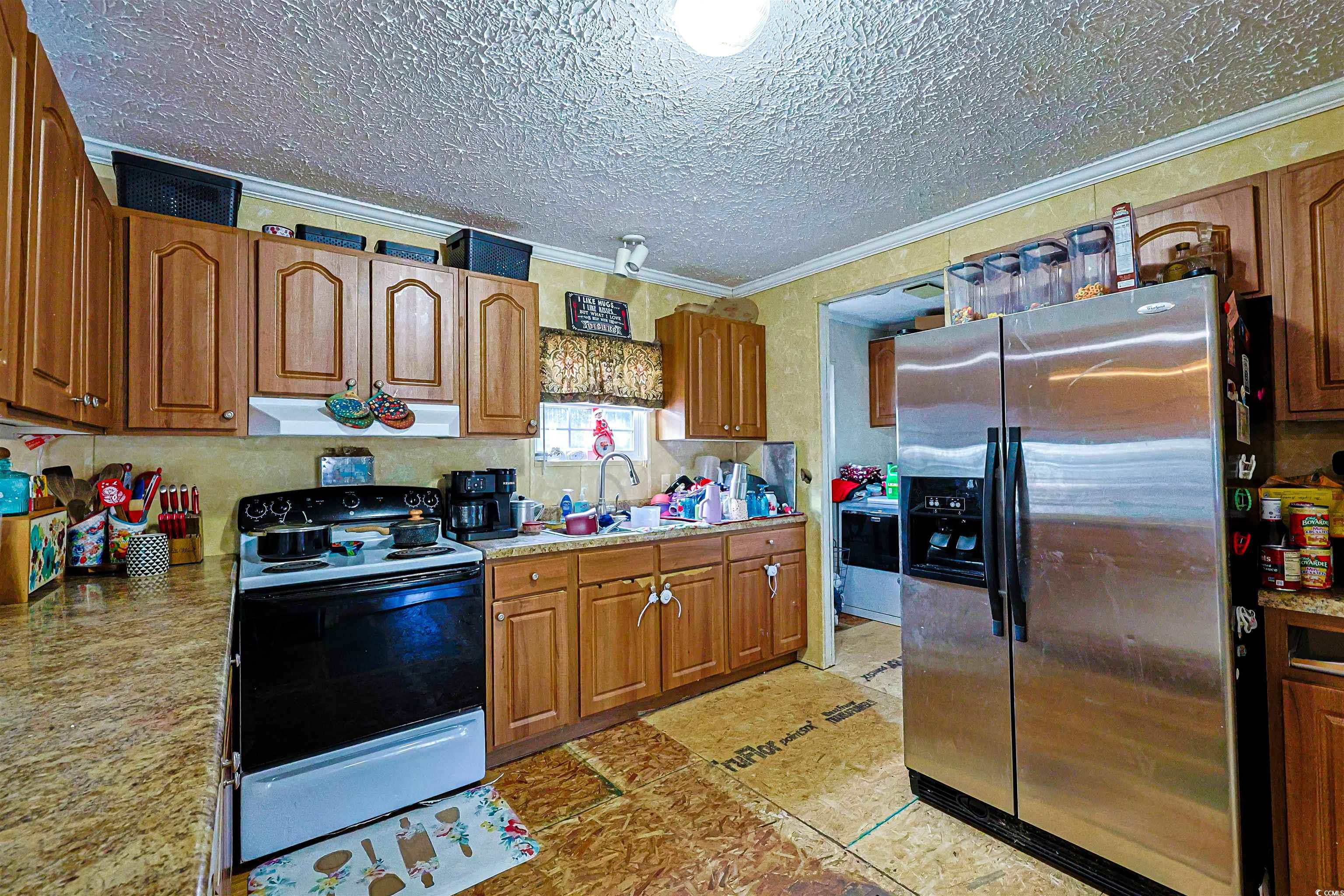 2128 Harvey Road Loris, SC 29569 - Photo 5 of 31 Kitchen featuring brown cabinetry, range with electric stovetop, stainless steel fridge with ice dispenser, ornamental molding, and under cabinet range hood