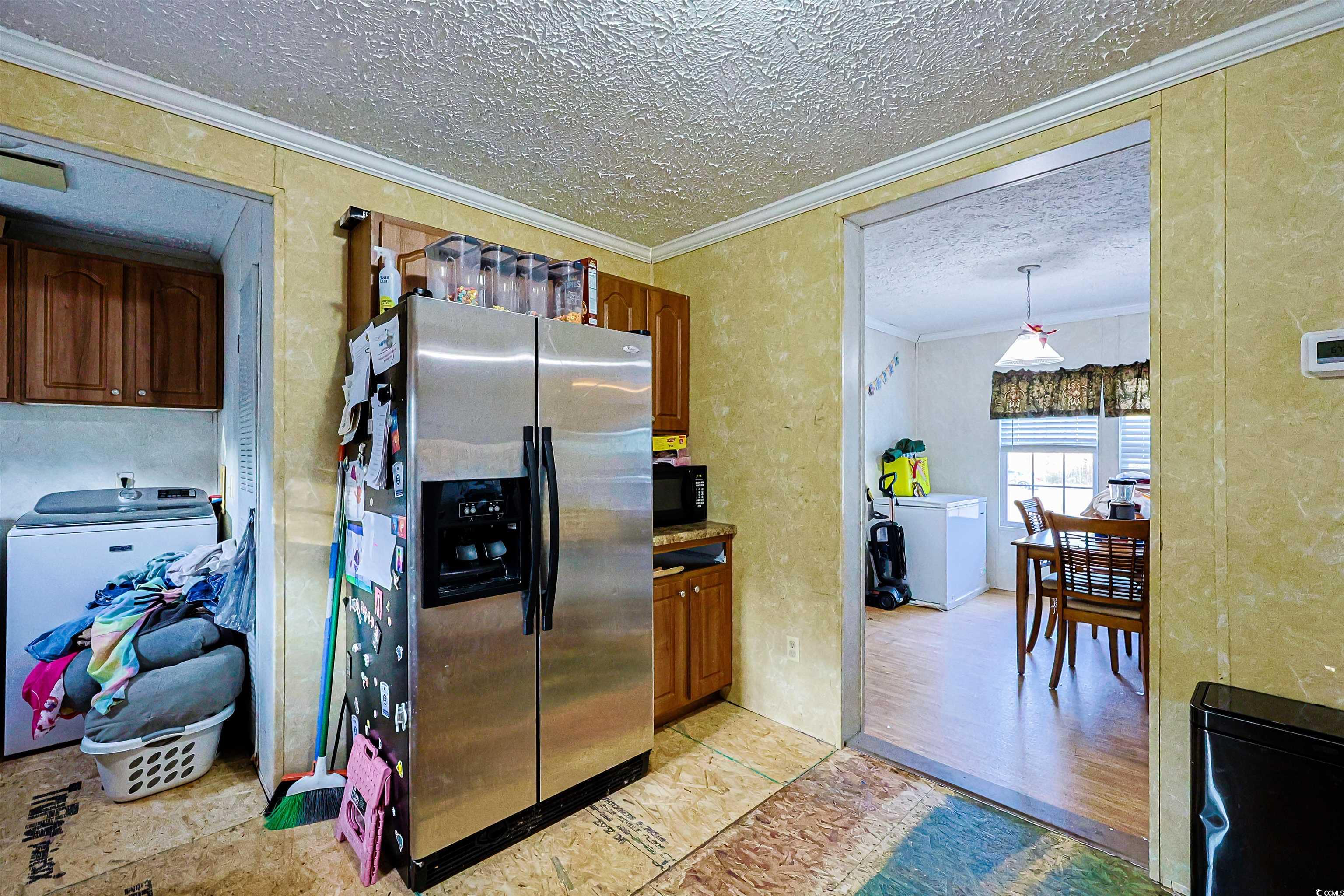 2128 Harvey Road Loris, SC 29569 - Photo 6 of 31 Kitchen featuring crown molding, stainless steel refrigerator with ice dispenser, a textured ceiling, white fridge, and decorative light fixtures