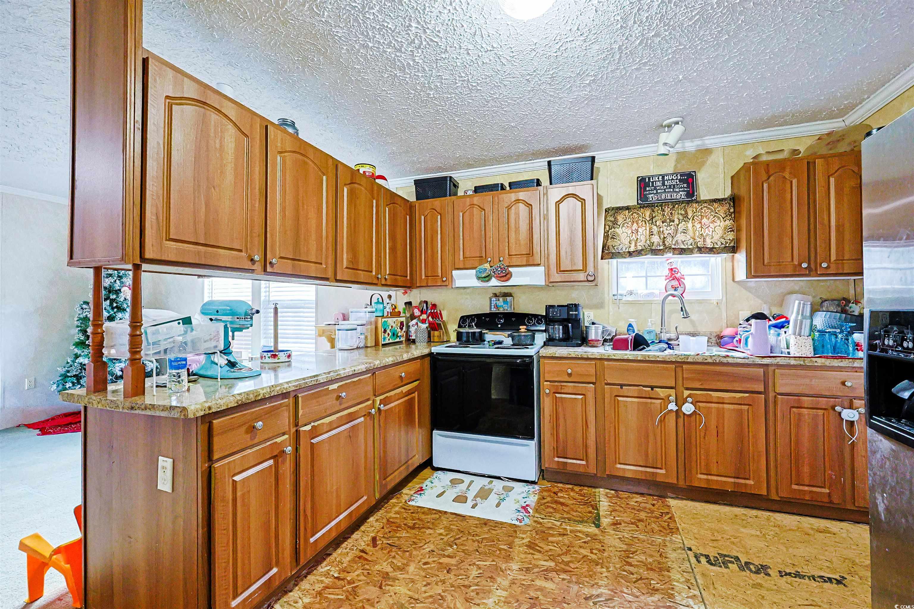 2128 Harvey Road Loris, SC 29569 - Photo 7 of 31 Kitchen featuring white electric range oven, brown cabinets, a textured ceiling, crown molding, and stainless steel refrigerator with ice dispenser