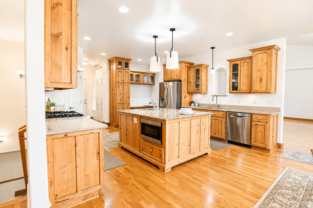 1055 North 1000 East Mapleton, UT 84664 - Photo 32 of 112 Spacious kitchen featuring light wood cabinetry, stone countertops, stainless steel appliances, a central island with a built-in microwave, and wood flooring