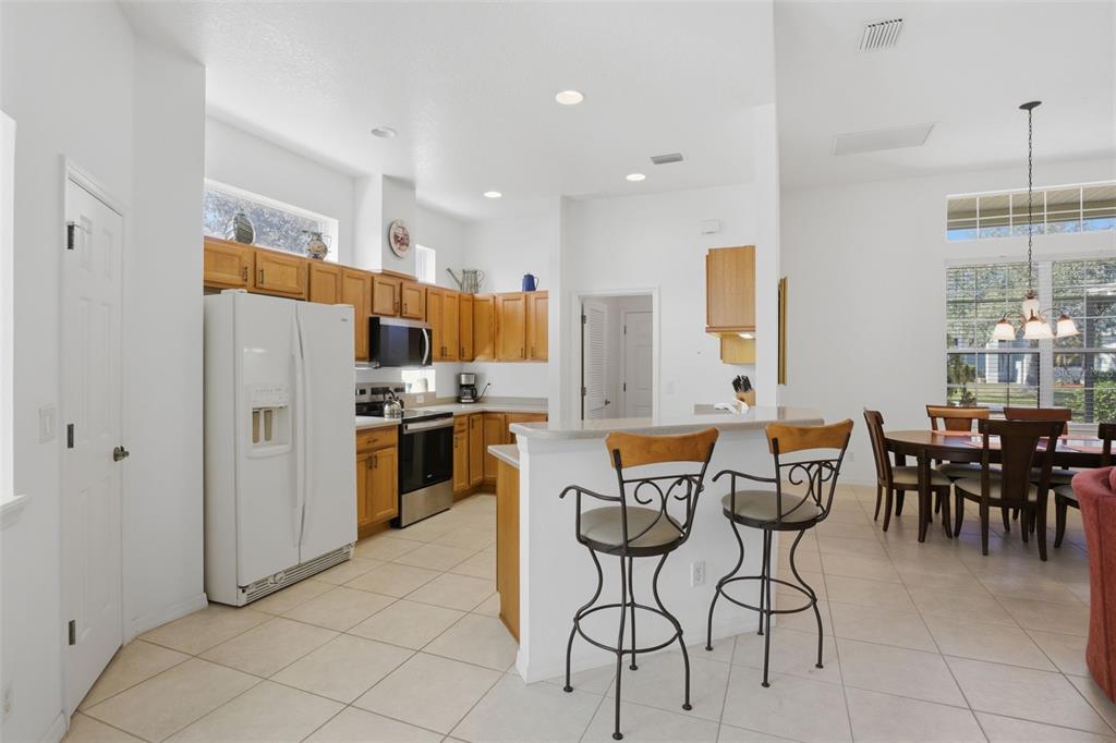 5922 Sage Leaf Place Leesburg, FL 34748 - Photo 12 of 39 a kitchen with stainless steel appliances a table chairs and a refrigerator