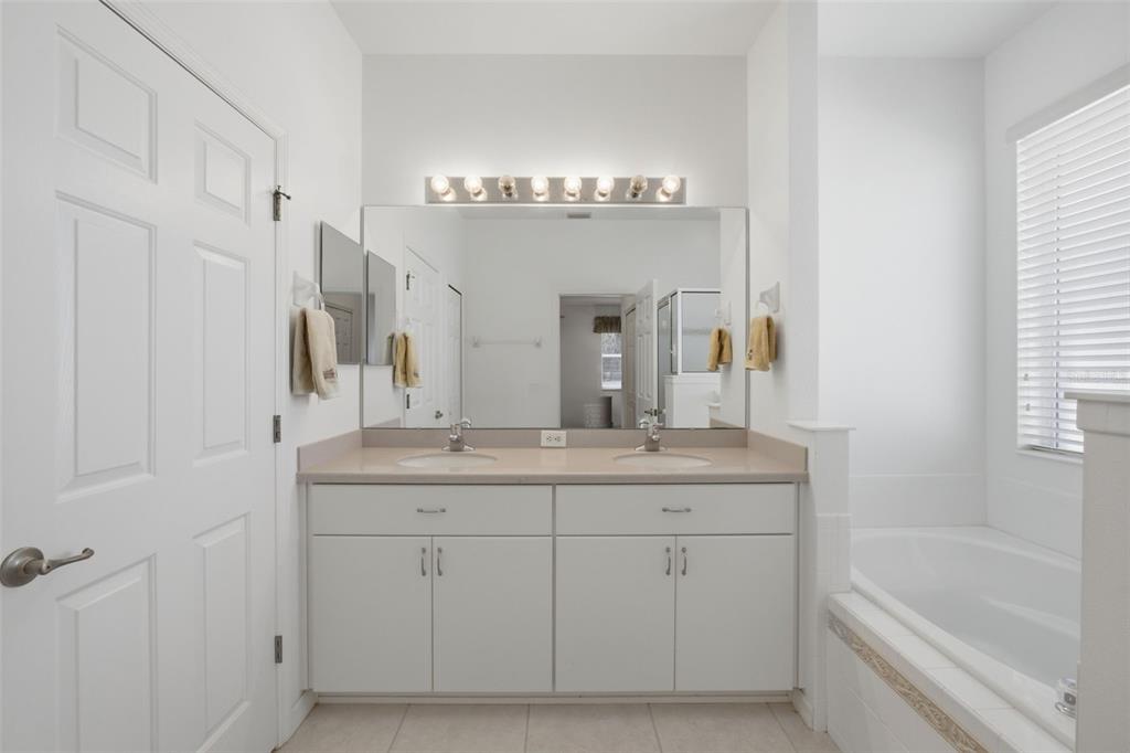 5922 Sage Leaf Place Leesburg, FL 34748 - Photo 17 of 39 a spacious bathroom with a granite countertop sink a mirror a and a bathtub