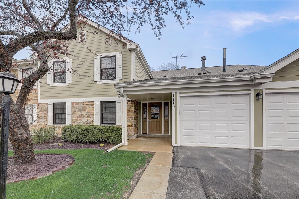 1110 Scanlon Drive, Unit D1 Wheeling, IL 60090 - Photo 1 of 23 a view of a white house next to a yard with big trees