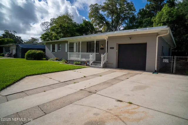 a front view of a house with a yard and potted plants