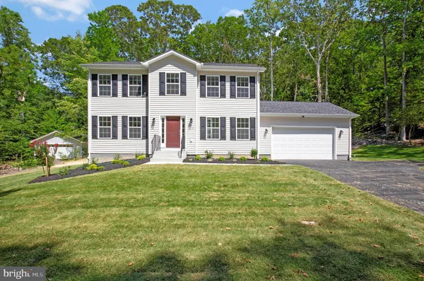 a front view of a house with a yard and trees