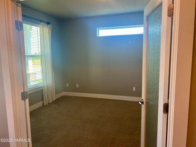 a view of an empty room with closet and a window
