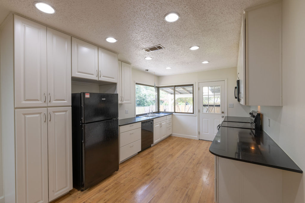 5310 Presidio Road Austin, TX 78745 - Photo 3 of 34 Functional kitchen with ample cabinetry, dark counters, and convenient access to the backyard.