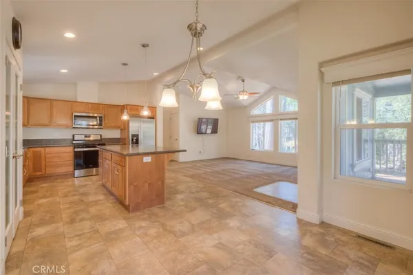 a kitchen with stainless steel appliances granite countertop a refrigerator a oven a sink a island and couches with wooden floor