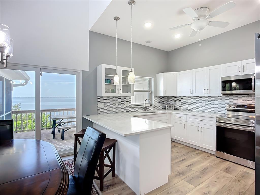 2424 69th Avenue West, Unit 2424 Bradenton, FL 34207 - Photo 10 of 49 a kitchen with stainless steel appliances granite countertop a stove top oven a sink dishwasher a dining table and chairs with wooden floor