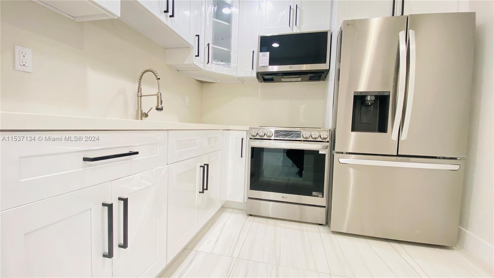 a kitchen with stainless steel appliances a refrigerator stove and white cabinets