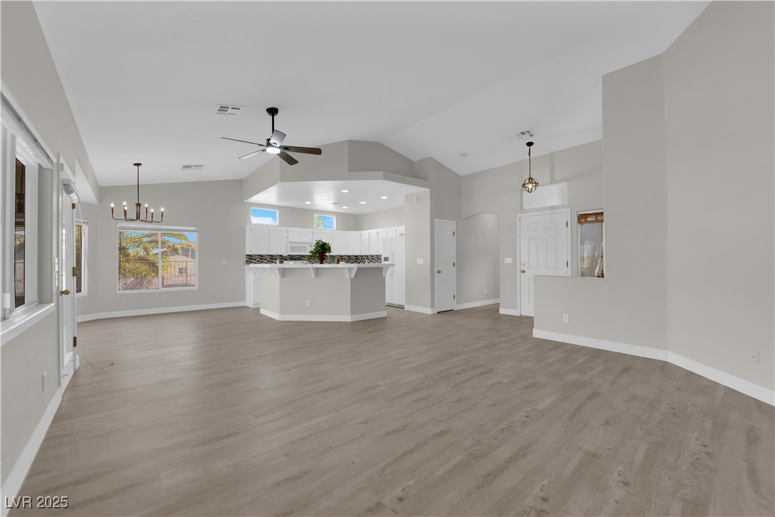 650 West Victory Road Henderson, NV 89015 - Photo 5 of 35 Unfurnished living room featuring vaulted ceiling, a chandelier, light wood-style floors, and ceiling fan