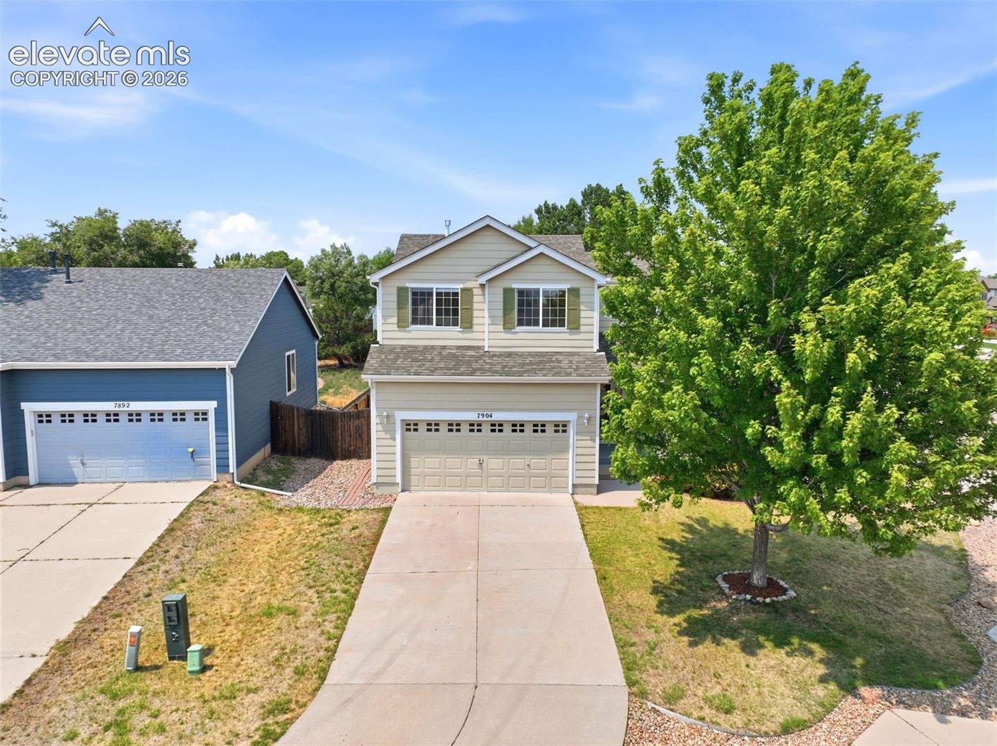 7904 Coffee Road Peyton, CO 80831 - Photo 39 of 48 Two-story residence featuring a two-car garage with panel detailing, light beige siding, and green window shutters