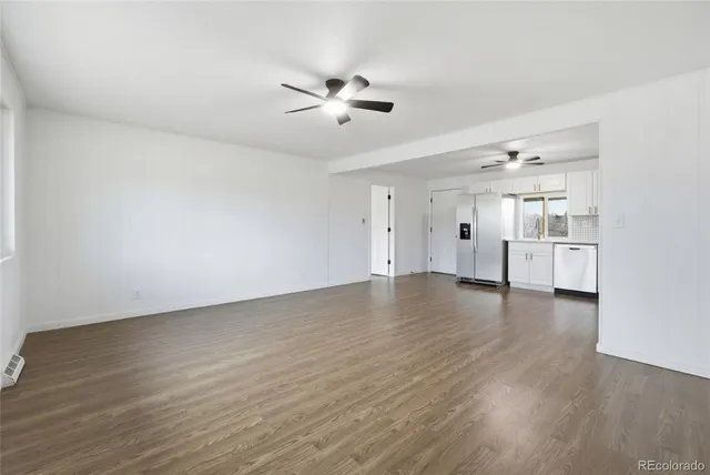 an empty room with wooden floor windows and ceiling fan
