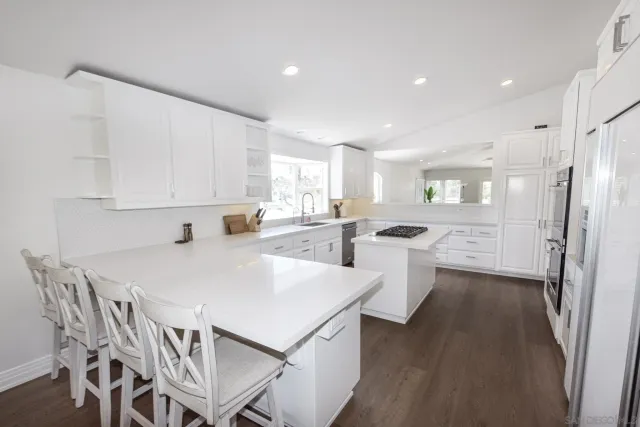 a kitchen with stainless steel appliances a refrigerator a stove a sink dishwasher and a dining table with wooden floor