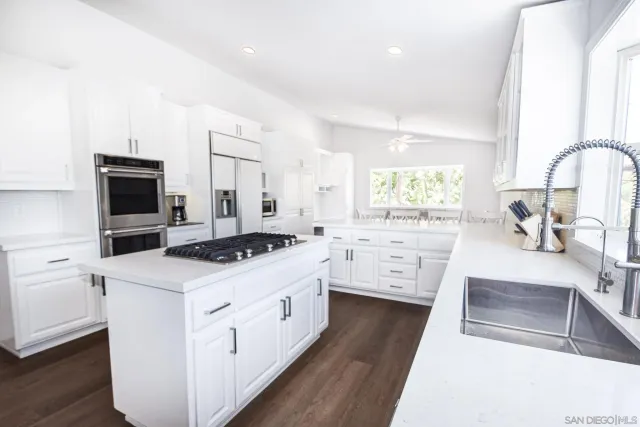 a kitchen with white cabinets and appliances