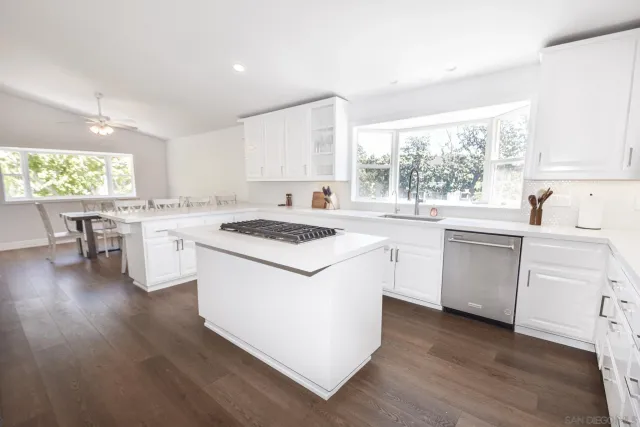 a kitchen with a sink a stove a refrigerator and white cabinets with wooden floor