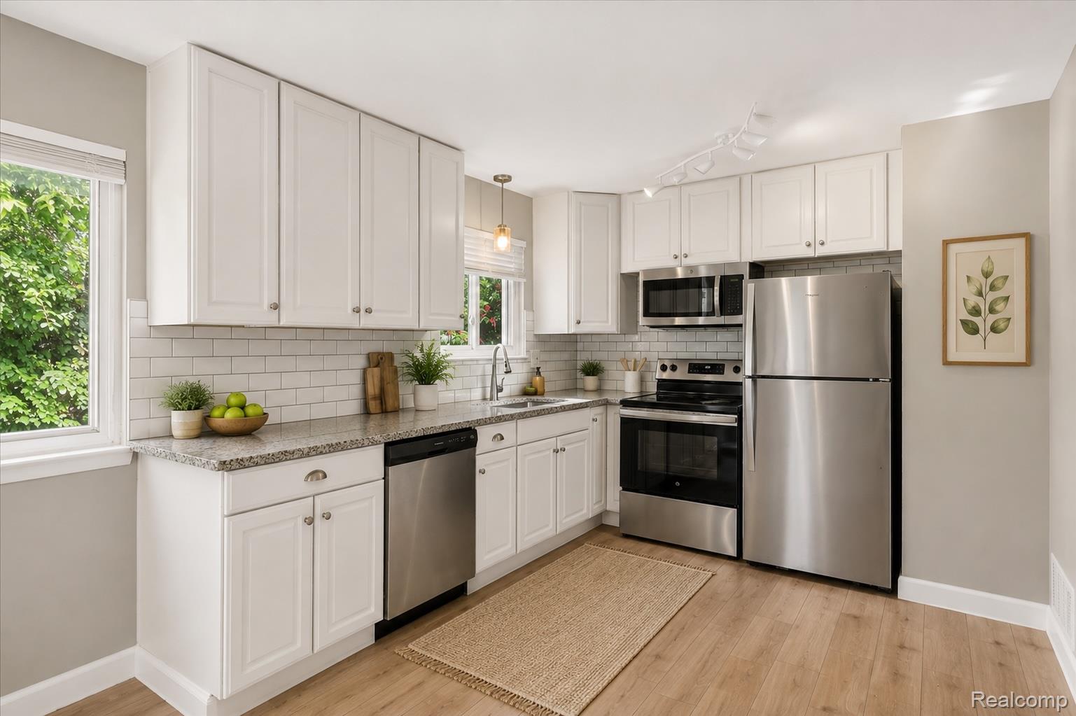 934 Harvard Road Berkley, MI 48072 - Photo 9 of 34 Modern kitchen featuring white shaker cabinetry, stainless steel appliances, speckled stone countertops, and a white subway tile backsplash