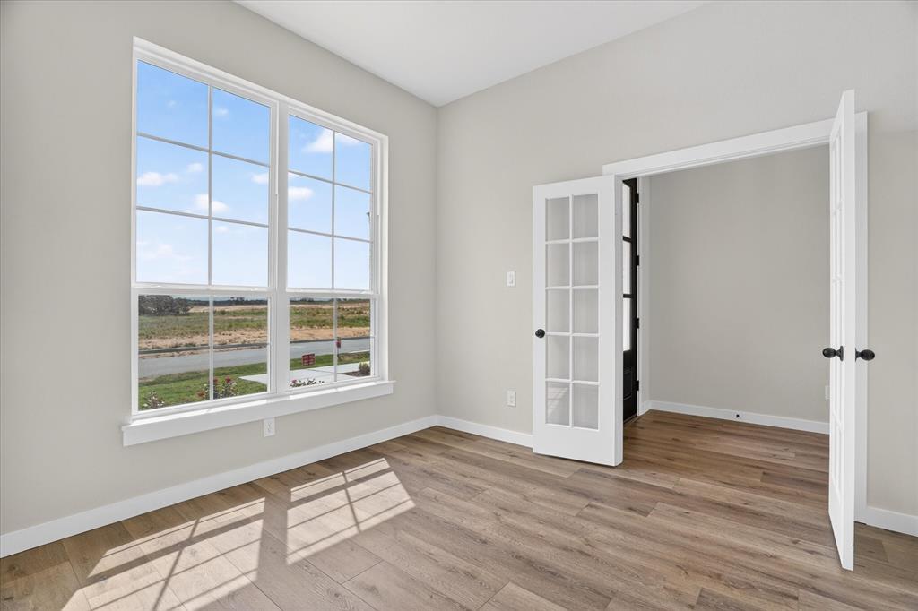 317 Skeen Peak Springtown, TX 76082 - Photo 12 of 31 Room featuring wood-finish flooring, a large multi-pane window with white trim, and a pair of French doors with black hardware
