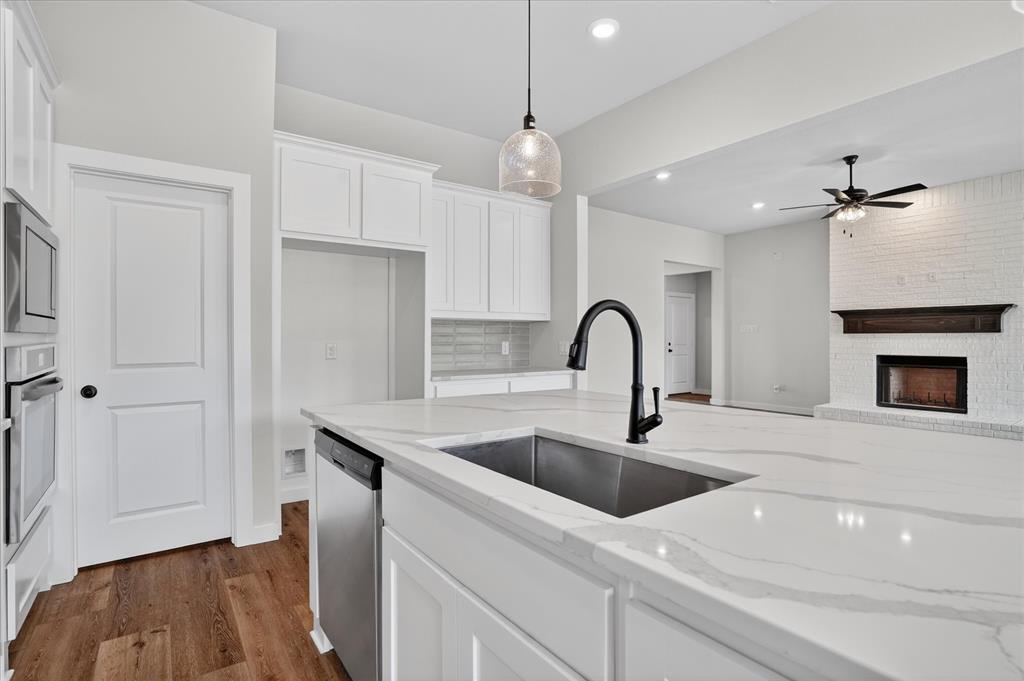 317 Skeen Peak Springtown, TX 76082 - Photo 7 of 31 Spacious kitchen island featuring a deep undermount sink with a matte black faucet, stainless steel dishwasher, and stone-finish countertop
