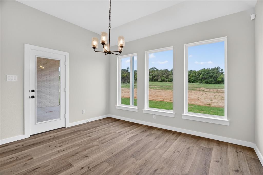 317 Skeen Peak Springtown, TX 76082 - Photo 8 of 31 Spacious room featuring wood-finish flooring, light grey walls, and a contemporary chandelier