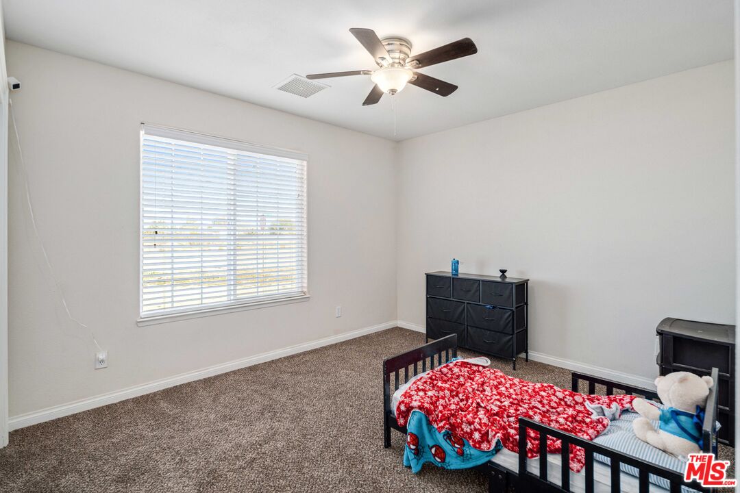 9516 Mendiburu Road California City, CA 93505 - Photo 22 of 32 a bedroom with a bed and a chandelier