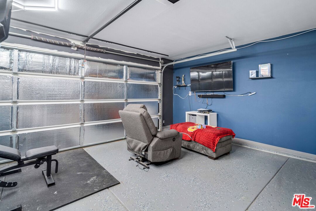 9516 Mendiburu Road California City, CA 93505 - Photo 26 of 32 a living room with furniture a flat screen tv and gym equipment