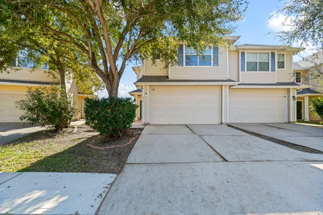 a view of a white house with a yard and large tree