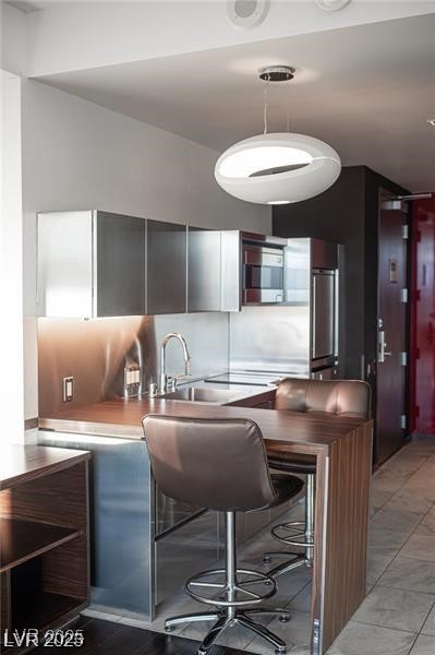 4381 West Flamingo Road, Unit 3303 Las Vegas, NV 89103 - Photo 35 of 37 Kitchen with decorative light fixtures, tasteful backsplash, light countertops, a sink, and stainless steel refrigerator