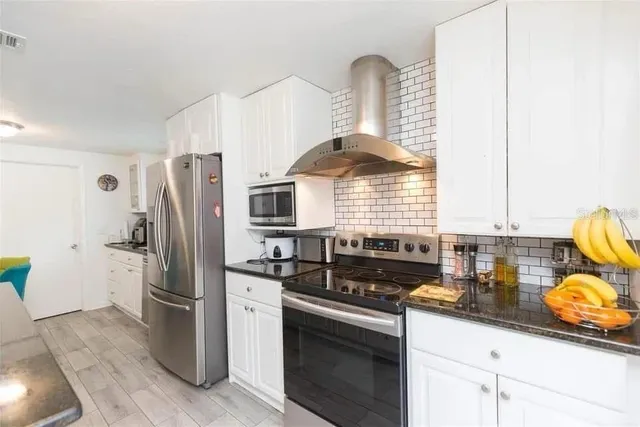 a kitchen with stainless steel appliances granite countertop a sink a stove and a refrigerator