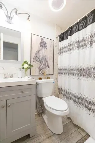 a bathroom with a granite countertop toilet sink and mirror
