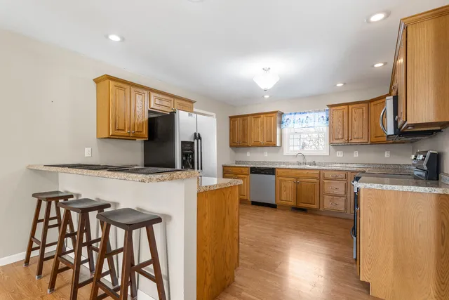 a kitchen with stainless steel appliances granite countertop a microwave a stove a sink dishwasher and a microwave oven with wooden floor