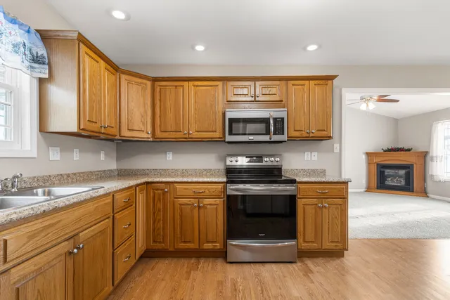 a kitchen with stainless steel appliances granite countertop a stove top oven a sink dishwasher and a microwave oven on the wooden floor