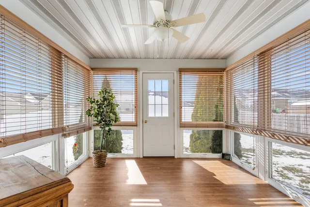 a view of empty room with wooden floor and fan