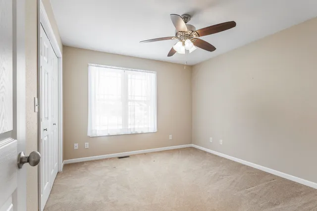 an empty room with windows and fan