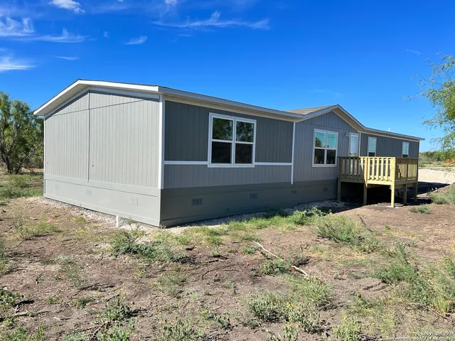 a view of house with yard and trees in the background