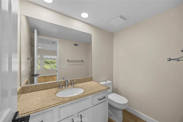 a bathroom with a granite countertop sink a toilet and a mirror