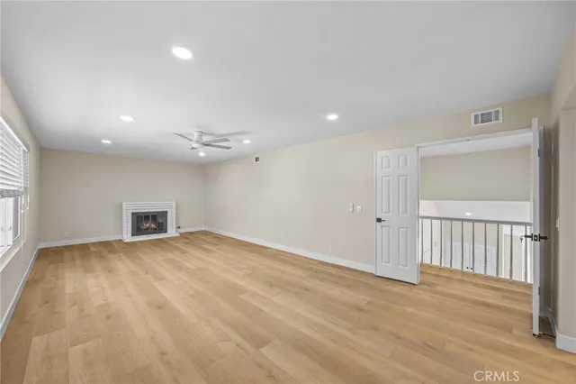 an empty room with wooden floor fan and windows