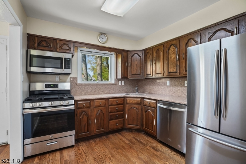 11 North Derby Road Springfield, NJ 07081 - Photo 6 of 30 a kitchen with granite countertop wooden cabinets stainless steel appliances and a window