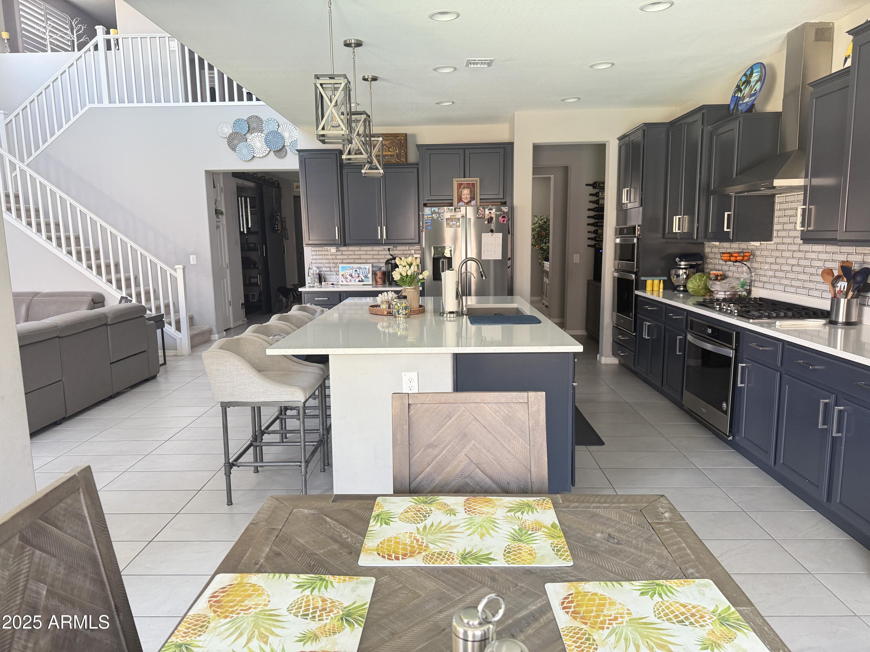 6980 West Redbird Road Peoria, AZ 85383 - Photo 6 of 31 a large kitchen with kitchen island a stove a sink dishwasher and wooden cabinets