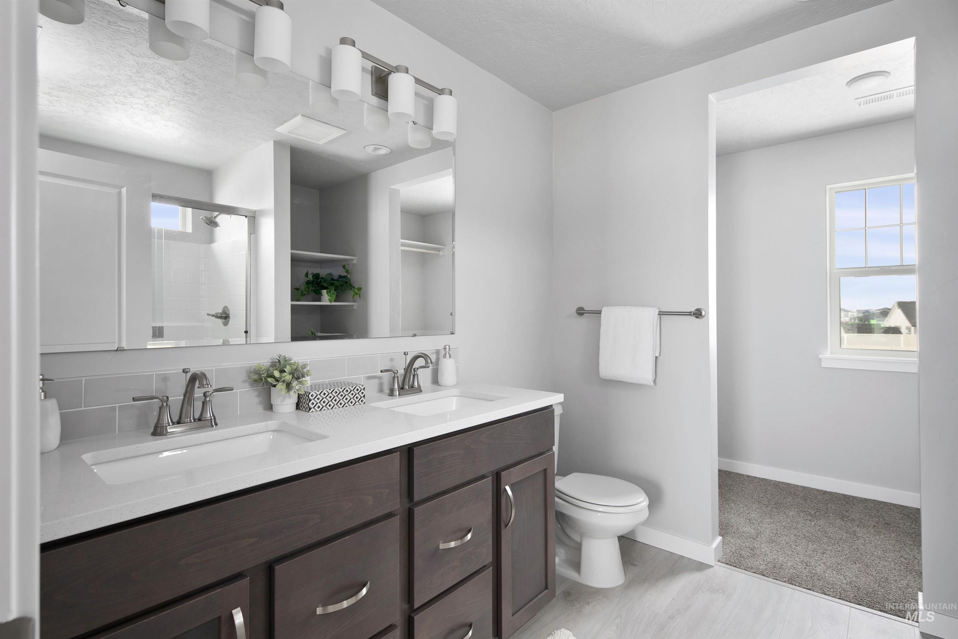 480 South Bobby Way Kuna, ID 83634 - Photo 6 of 9 Bathroom featuring a shower stall, double vanity, a textured ceiling, and tasteful backsplash