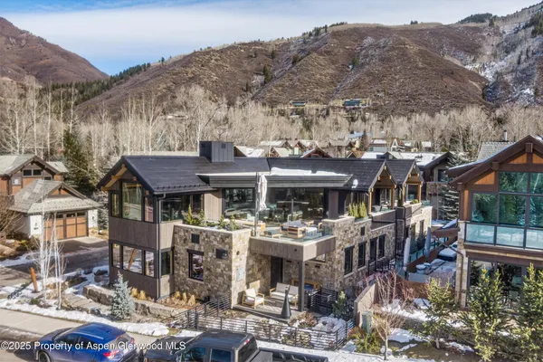 a front view of a house with a mountain view and large trees
