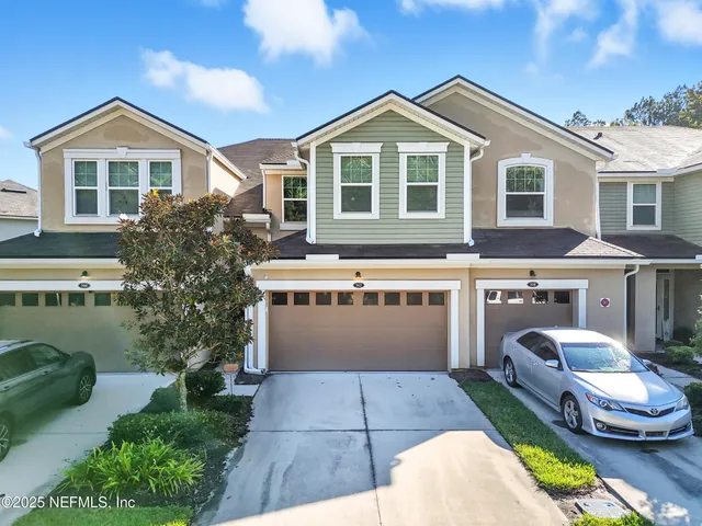 a front view of a house with a yard and potted plants