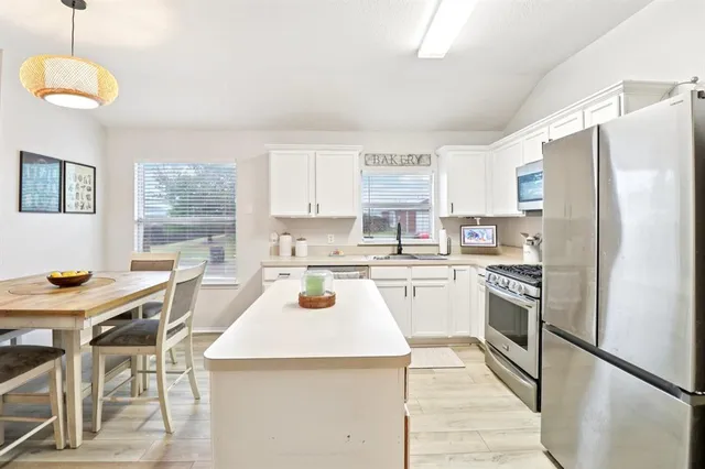 a kitchen with a refrigerator a stove a sink dishwasher with a dining table and chairs