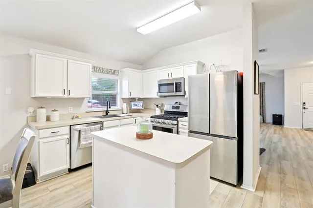 a kitchen with a sink a refrigerator a microwave and cabinets