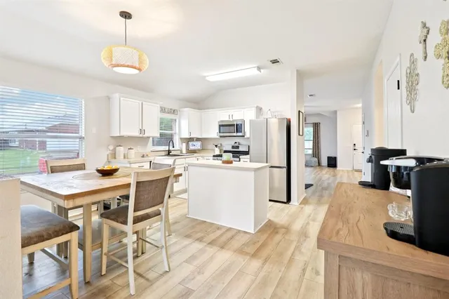 a kitchen with a table chairs refrigerator and microwave