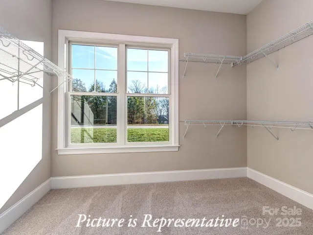 a view of an empty room with a window and hardwood floor